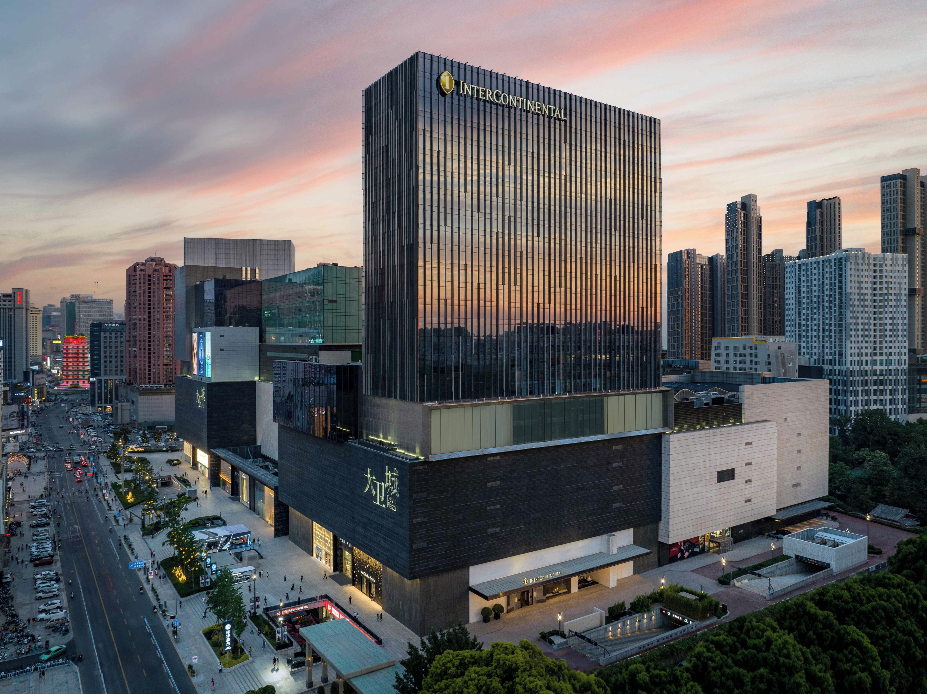 Een modern hotelgebouw met een opvallend 'INTERCONTINENTAL' bord, omgeven door een drukke stadsstraat en andere hoogbouw.