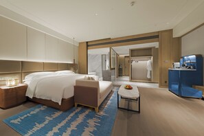 A modern hotel room with a large bed, bedside tables, a small table with fruit, and a blue patterned rug. - Intercontinental Zhengzhou (Zhengzhou)