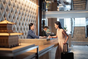 A reception desk with a modern geometric wall design, a model of a building, and a staircase in the background. - Intercontinental Zhengzhou (Zhengzhou)