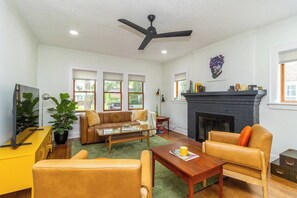 Un salon avec une cheminée, un ventilateur de plafond et un téléviseur.