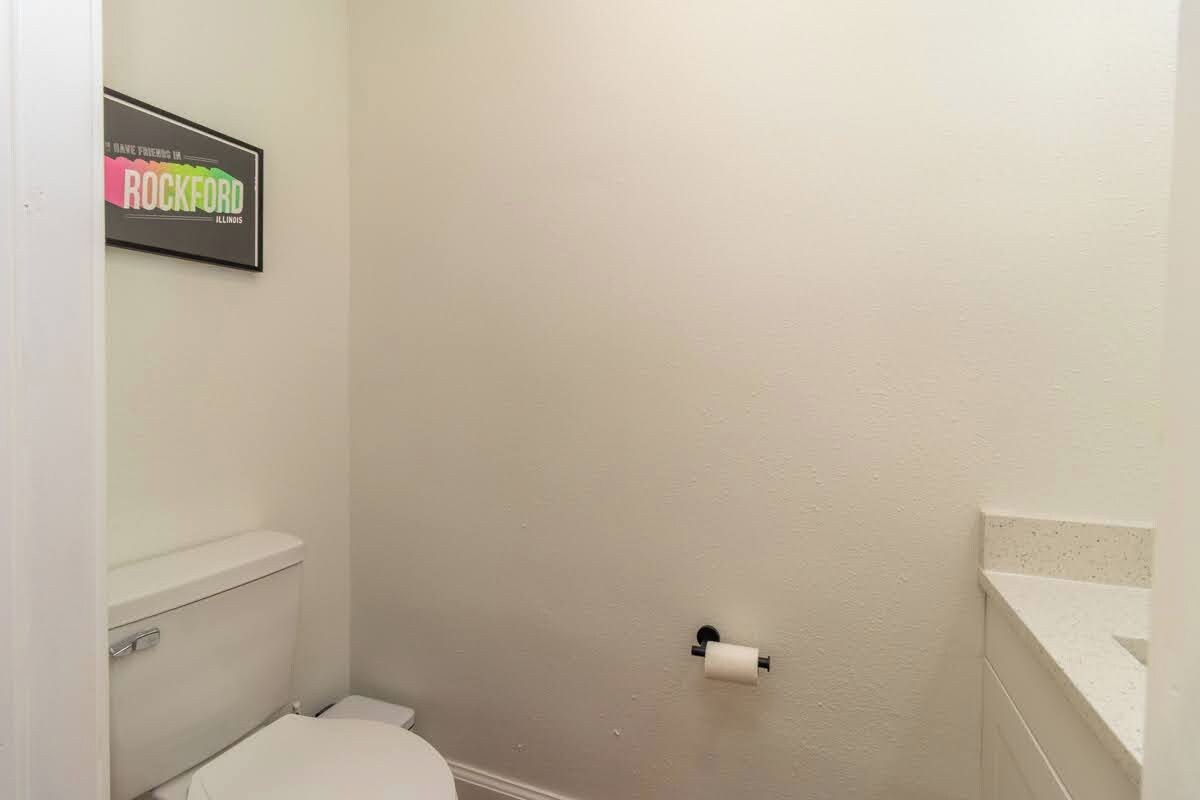 A bathroom with a toilet, a shower, and a toilet paper holder on the wall.
