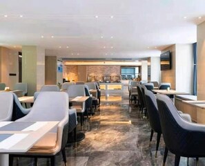 A modern hotel dining area with multiple tables and chairs, a central bar area, and a stone accent wall. - Lavande Hotel (Tongzhou)