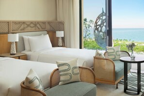 A hotel room with two beds, a sitting area with wicker chairs, a small table, and a view of the sea. - Intercontinental The Red Sea Resort by IHG (Umluj)