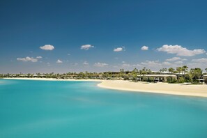 A beach resort with a clear blue sky, sandy beach, and resort buildings.