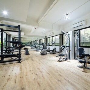 A gym with various exercise equipment, large windows, and a wooden floor. - College Haus Rangnam (Bangkok)