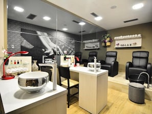Un spa moderno con un mostrador de recepción, sillas de cuero negro, un espejo grande y un estante con objetos decorativos.