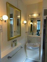 Un baño con un espejo grande, un lavamanos y luces empotradas en la pared.