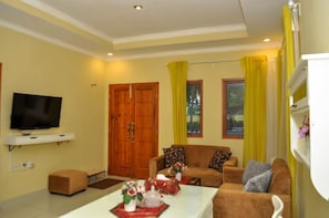 Una sala de estar con un televisor, dos sofás, una mesa de centro y una puerta de madera.