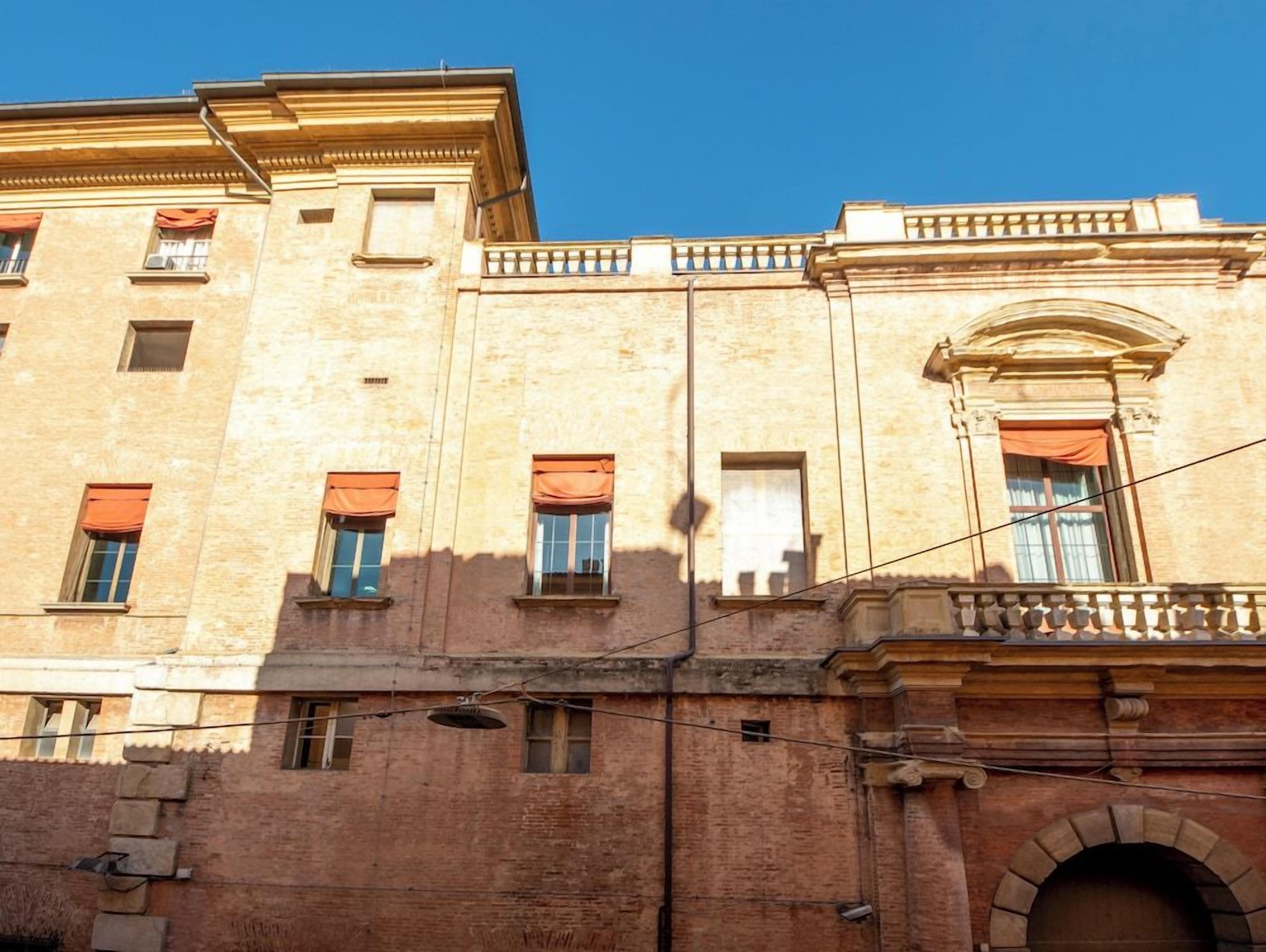 A multi-story building with a classical architectural style, featuring arched windows and a balcony with a balustrade.