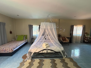 Une chambre avec un lit à baldaquin, un canapé-lit, un bureau avec une chaise et un ventilateur.