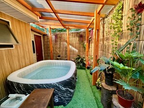 Ein Wellnessbereich mit Whirlpool, einer Holzterrasse und einer Bambuswand.