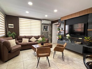 A modern living room with a sofa, two armchairs, a coffee table, and a flat-screen TV. - Mountain Cabin with Private Hot Tub in San José de Maipo 0194A (El Manzano)