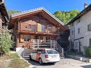 Eine Holzhütte mit einem parkenden Auto davor.
