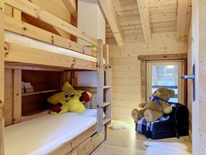 Habitació amb un llit doble de fusta, un os de peluix i un coixí amb forma de marieta.