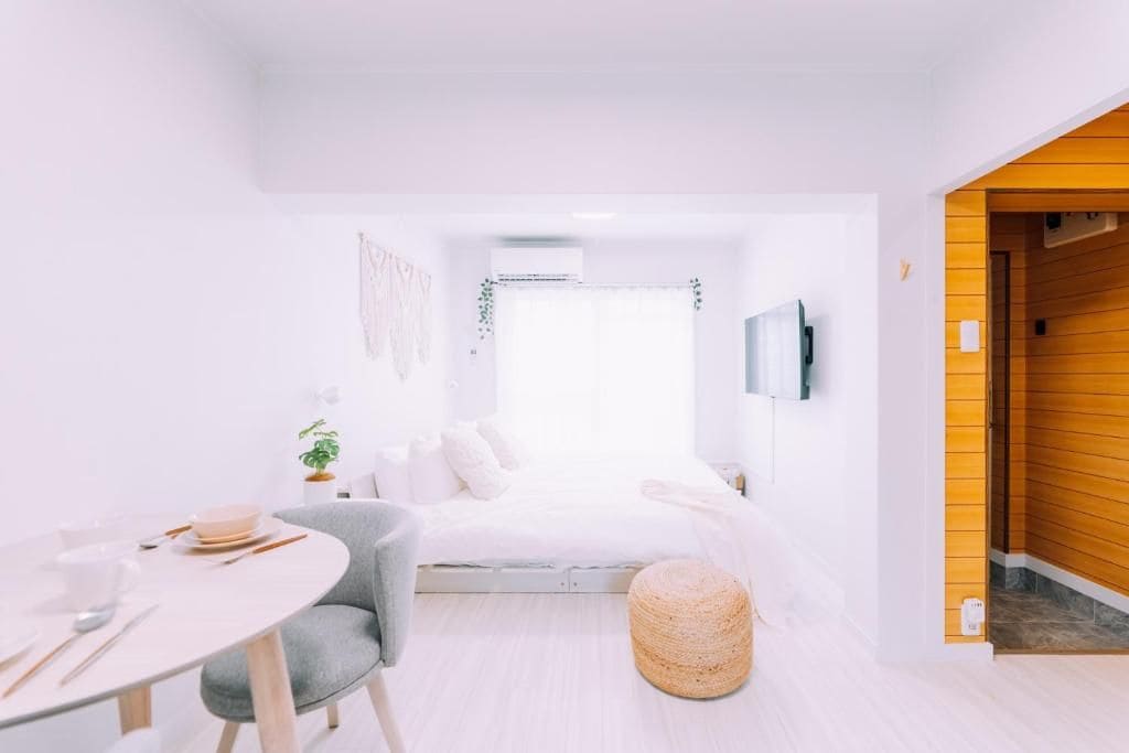 A modern bedroom with a bed, bedside table, and a round ottoman.