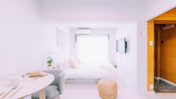 A modern bedroom with a bed, bedside table, and a round ottoman.