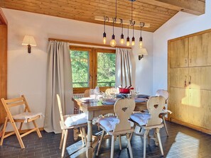 Ein Essbereich mit einem Holztisch, gedeckt für vier Personen, umgeben von Stühlen mit herzförmigen Rückenlehnen.