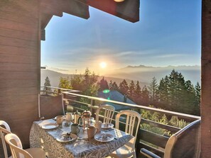 Ein Tisch für zwei Personen mit Blick auf ein Bergmassiv und die Sonne im Hintergrund.