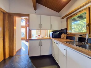 Eine moderne Küche mit weißen Schränken, einer Edelstahl-Spüle und einem Fenster mit Blick auf Grünflächen.
