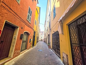 A narrow cobblestone street flanked by buildings with doors and windows, leading to a distant view. - Cosy apartment for 5 guests with WIFI, A/C and TV (Riva Ligure)