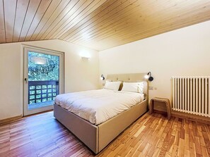 Ein Schlafzimmer mit einem Bett, einem Heizkörper, einer Tür zu einem Balkon und einem kleinen Tisch.