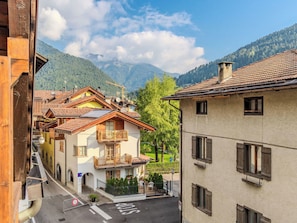 Straßenansicht mit Gebäuden, blauem Himmel und Bergen im Hintergrund.