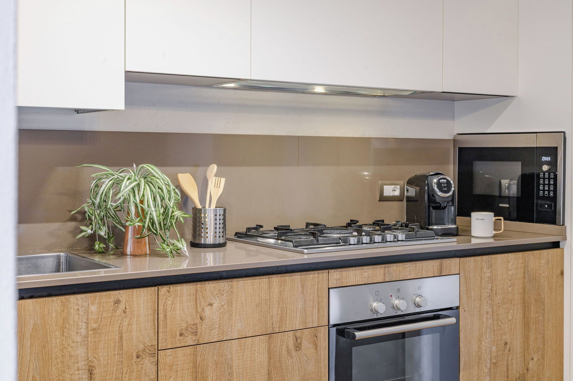 Eine moderne Küche mit Gasherd, Kaffeemaschine und Backofen.