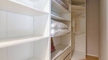 A closet with multiple shelves and drawers, some containing folded items.