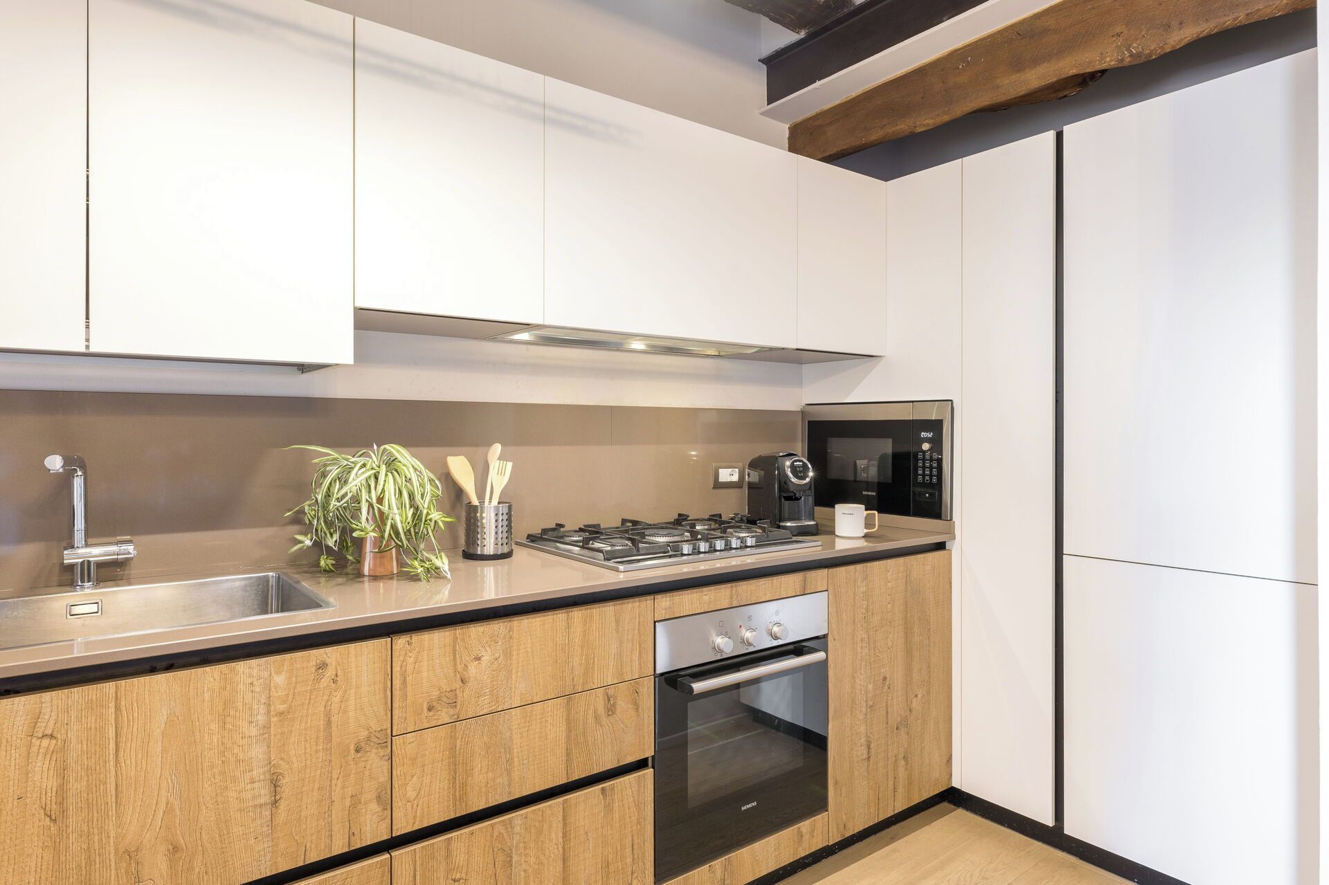 Een moderne keuken met houten kastjes, een ingebouwde gasfornuis, een magnetron en een oven.