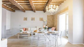 Een moderne eethoek met een houten plafond, een kroonluchter en een bakstenen muur.