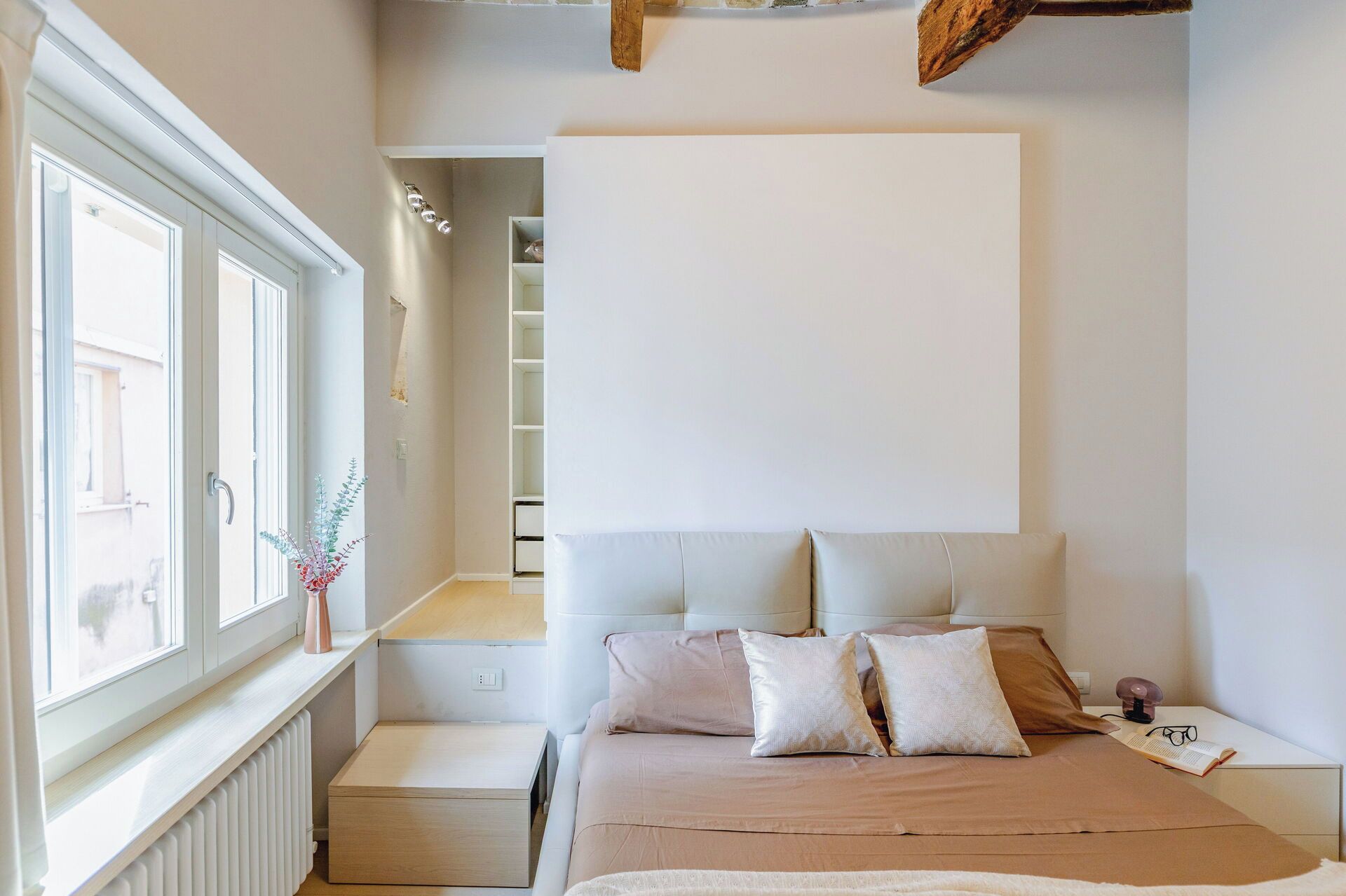 Ein Schlafzimmer mit Bett, Nachttisch und Fenster.