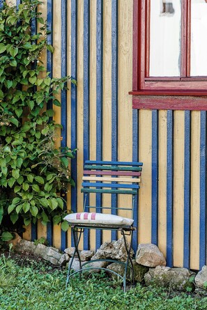 A bench with a cushion against a wall with vertical stripes.