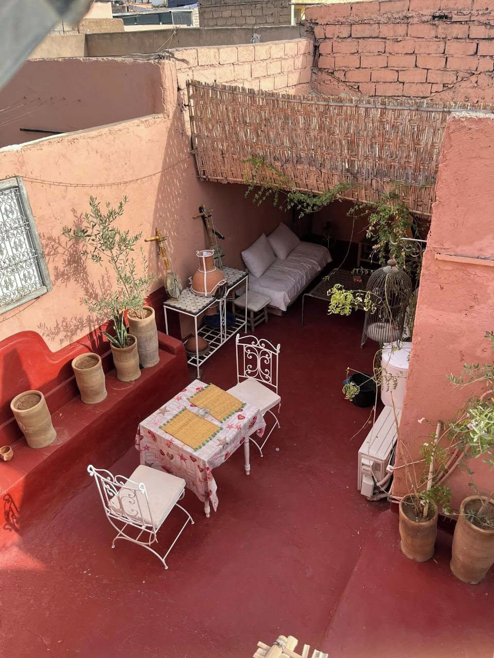 Uma área de estar externa aconchegante com mesa, cadeiras e plantas em vasos.