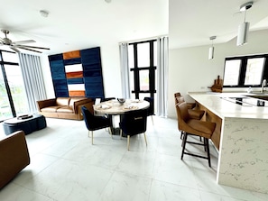 Un espace de vie moderne comprenant un coin repas, un canapé, une table basse et un coin cuisine avec un plan de travail et un évier.