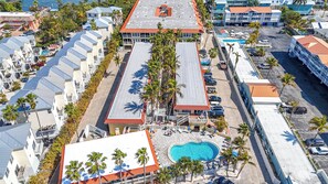 An aerial view of a resort with multiple buildings, a swimming pool, and palm trees. - Tortuga Inn Beach Resort #219 | Direct Gulf & Beach Views (Bradenton Beach)
