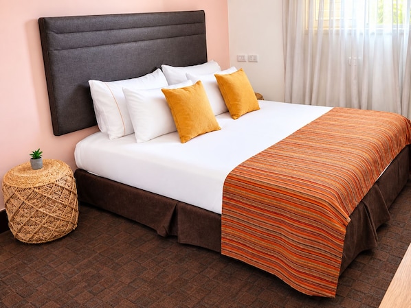 A neatly made bed with a dark headboard, white bedding, and two mustard-colored pillows.