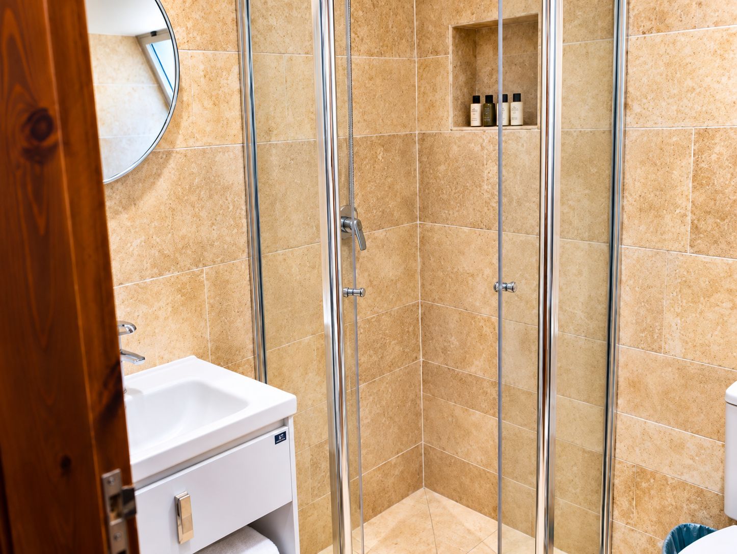 A bathroom with a glass-enclosed shower, a white sink, and a mirror.