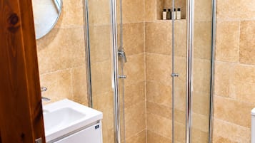 A bathroom with a glass-enclosed shower, a white sink, and a mirror.