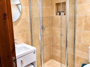 A bathroom with a glass-enclosed shower, a white sink, and a mirror.