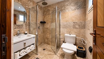 A modern bathroom with a glass-enclosed shower, a toilet, and a sink with a mirror.