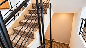 Una escalera con alfombra a cuadros y barandillas de metal negro.
