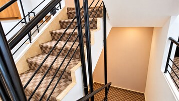 Una escalera con alfombra a cuadros y barandillas de metal negro.