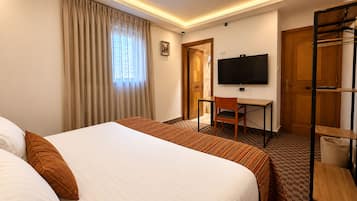 Ein Hotelzimmer mit Bett, Schreibtisch, Fernseher und Kleiderschrank.