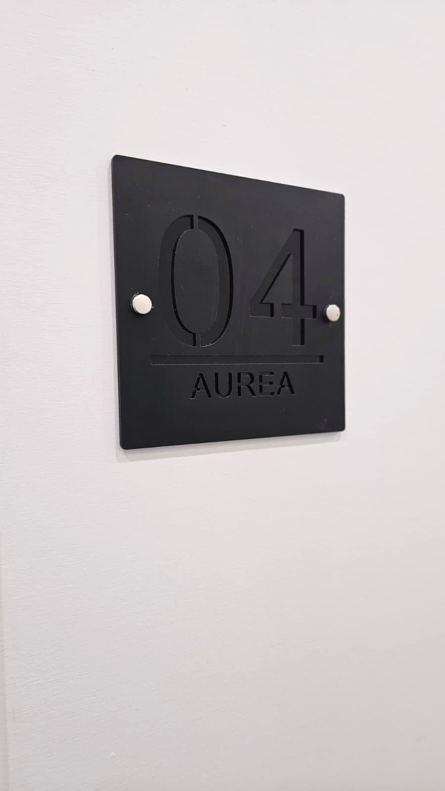 A black wall-mounted sign with the number '04' and the word 'AUREA' below it.