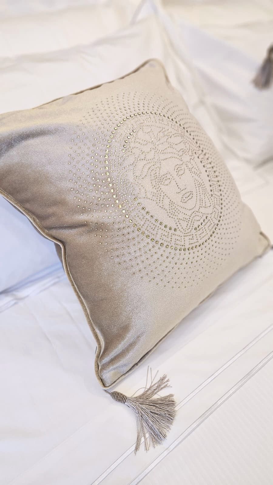 A pillow with a tassel on a bed.