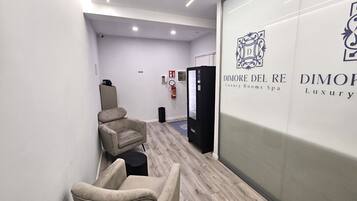Ein Flur mit einem Massagesessel, einem Feuerlöscher und einer Wand mit dem Logo und Text für 'DIMORE DEL RE Luxury Rooms Spa'.