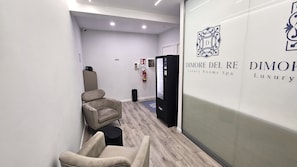 Un pasillo con una silla de masaje, un extintor y una pared con un logotipo y texto para 'DIMORE DEL RE Luxury Rooms Spa'.