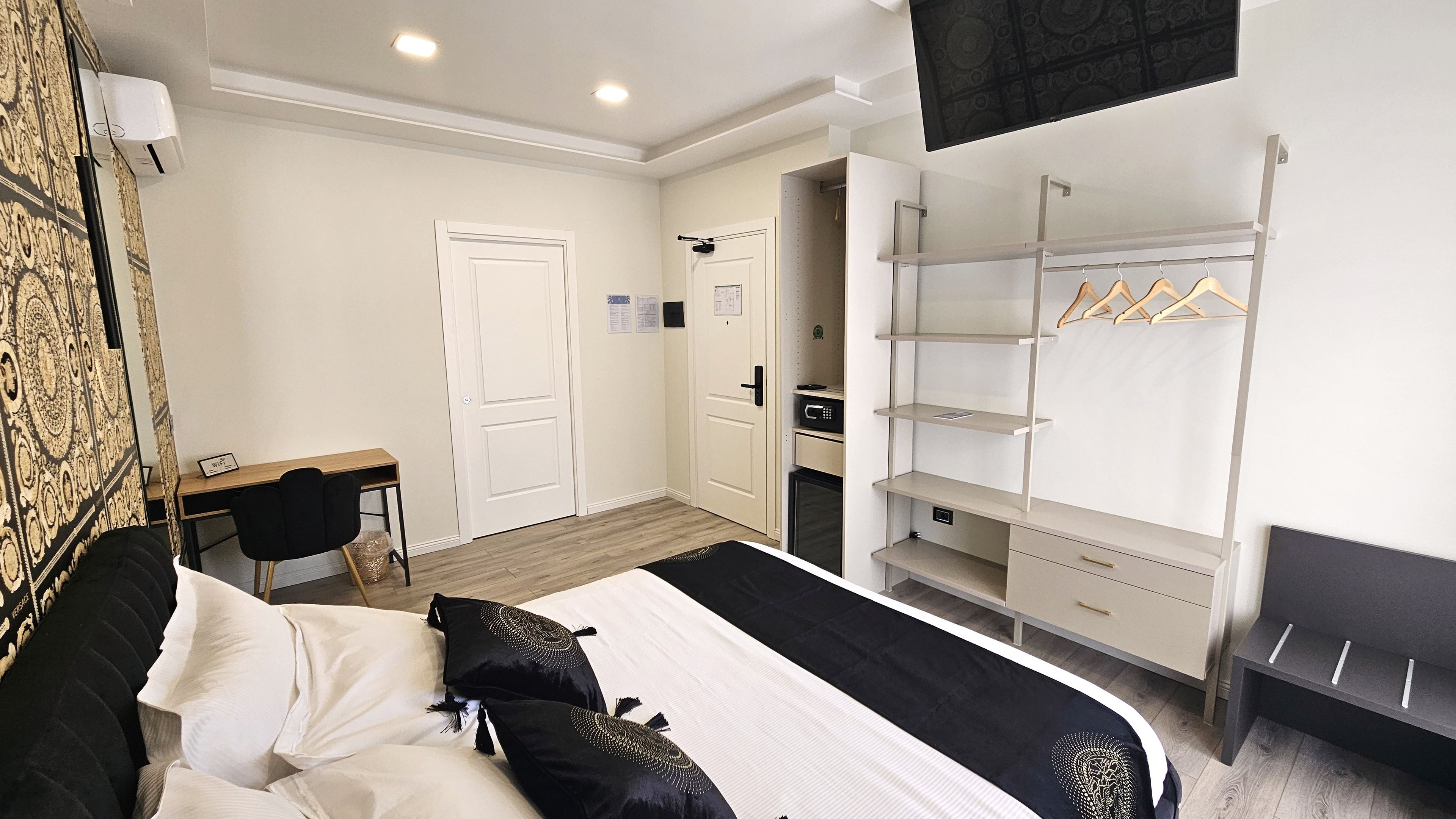 A hotel room with a bed, a desk, a wardrobe, and a microwave.