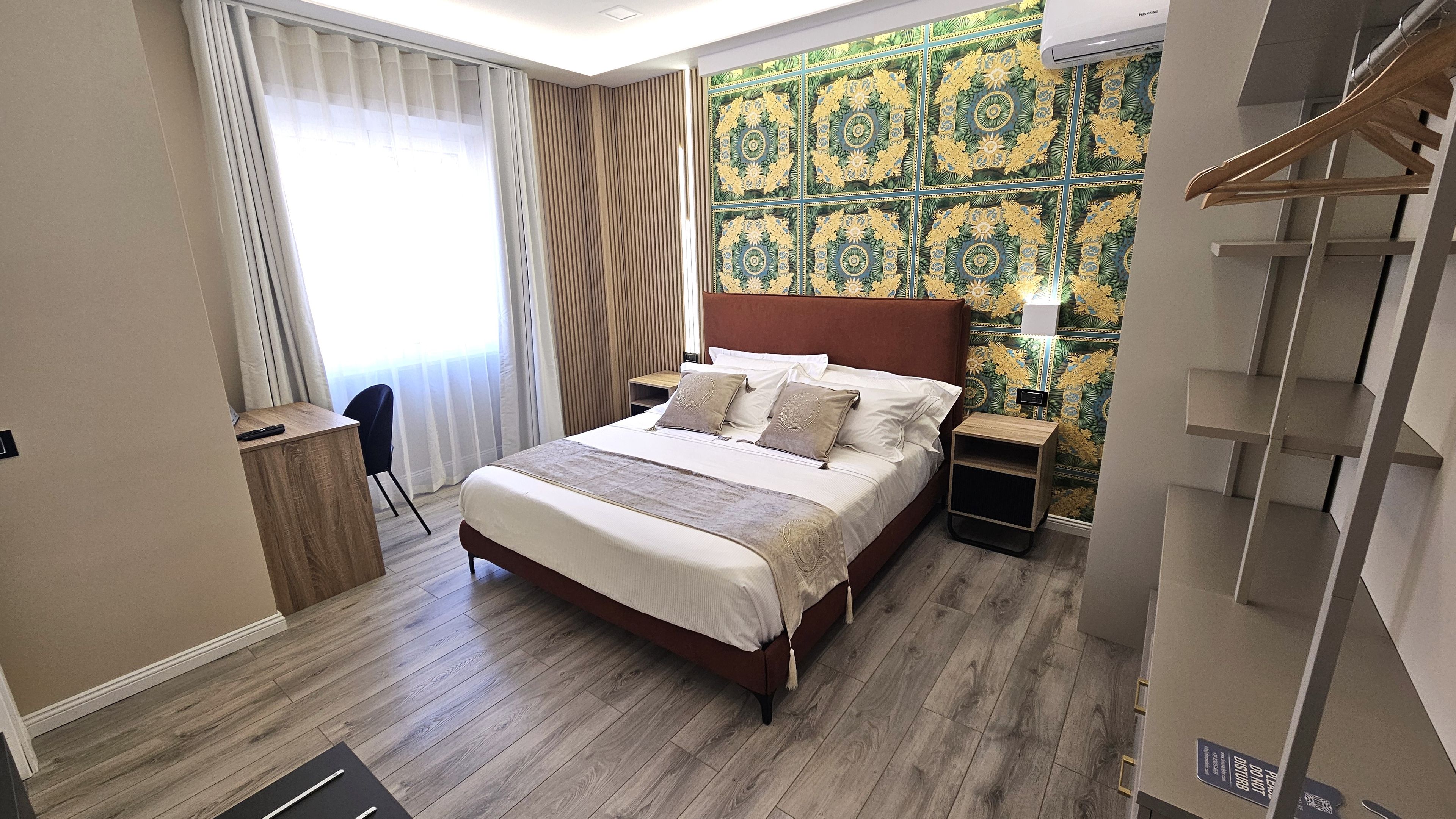 Una camera d'albergo con un letto, comodini, una scrivania e una sedia.