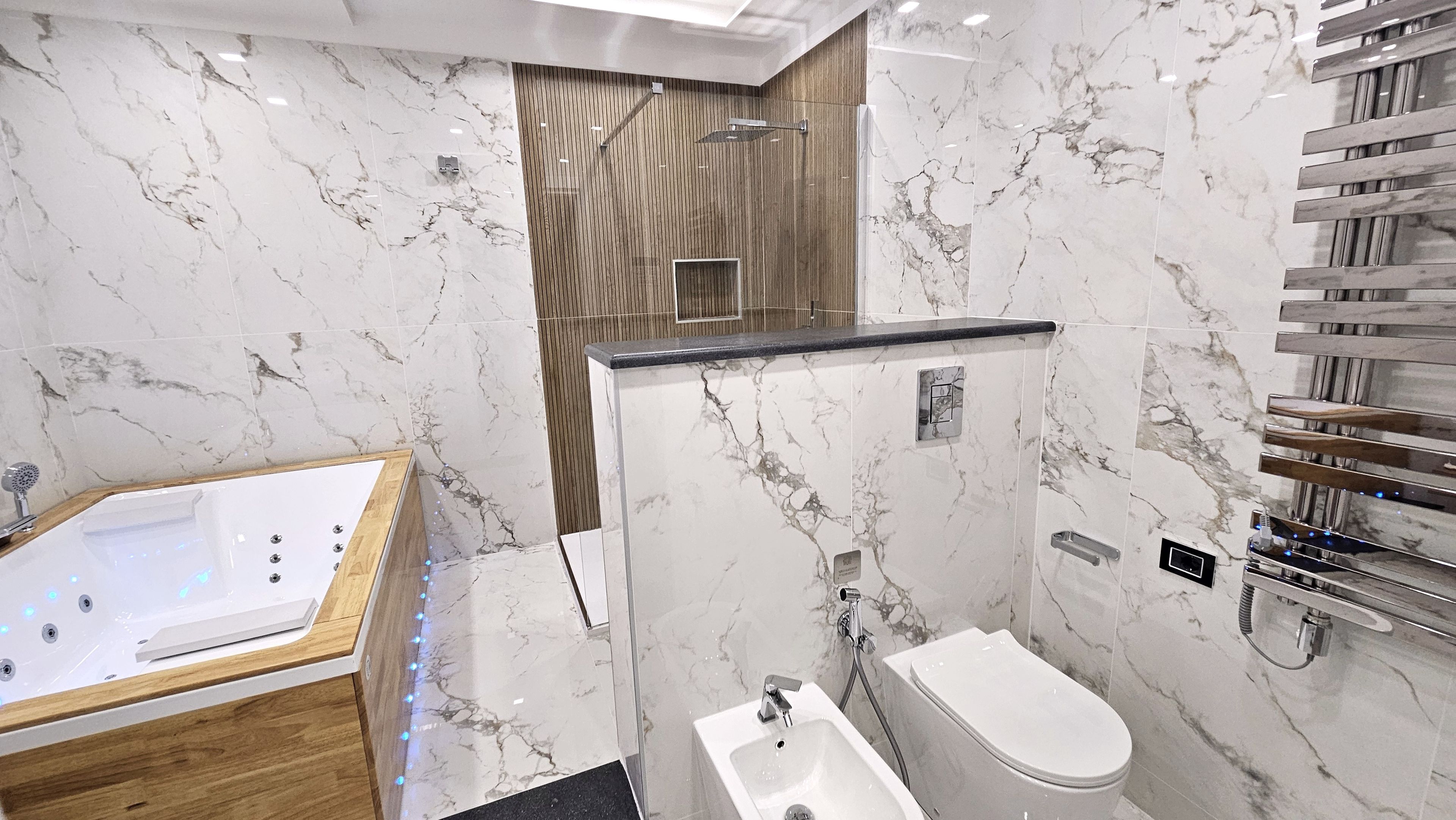 Un baño moderno con suelo de mármol, una bañera independiente, cabina de ducha y un inodoro.